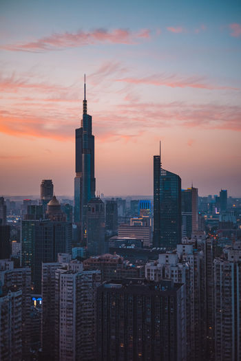Modern buildings in city against sky during sunset