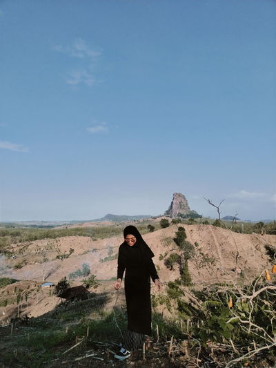 Young woman in hijab standing on land against sky