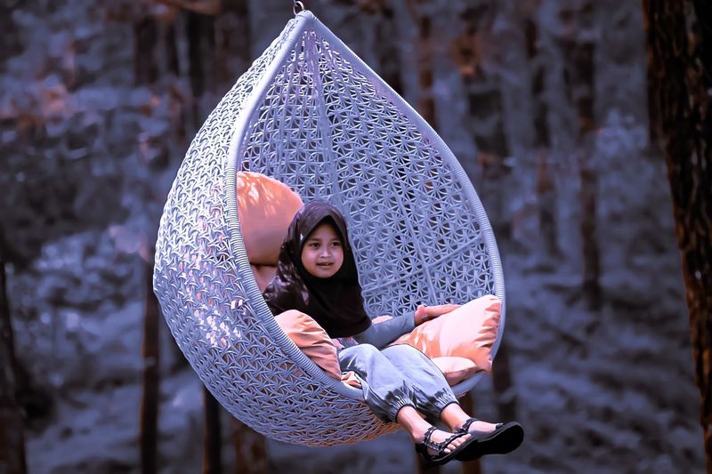 Portrait of young woman holding umbrella against trees