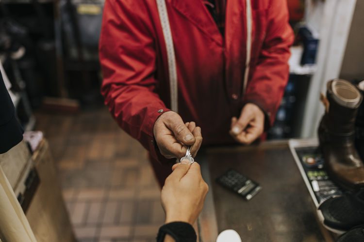 Locksmith giving key to female customer in repair shop