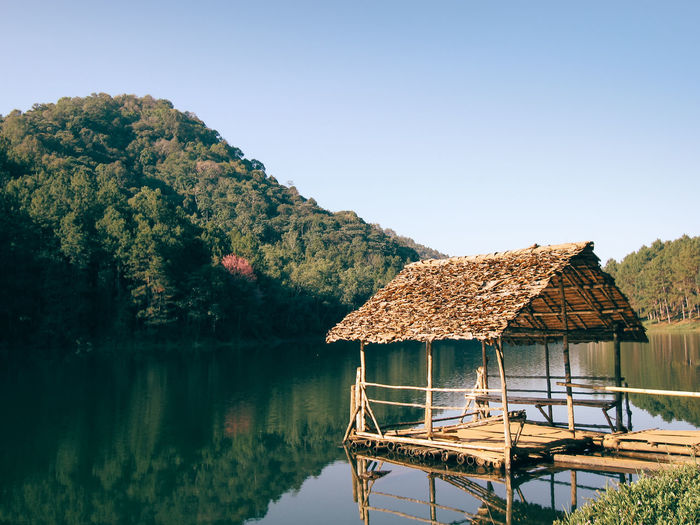 Built structure by lake and buildings against clear sky