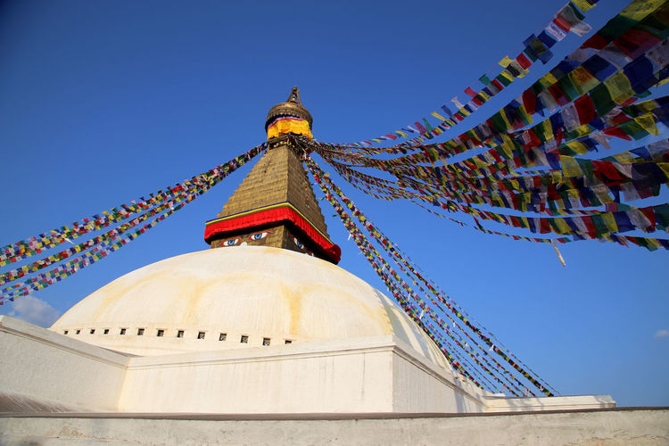 Low angle view of prayer flags on bodnath stupa against sky