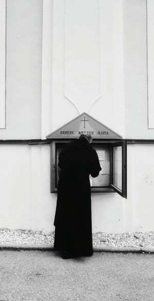 Rear view of priest standing in front of church