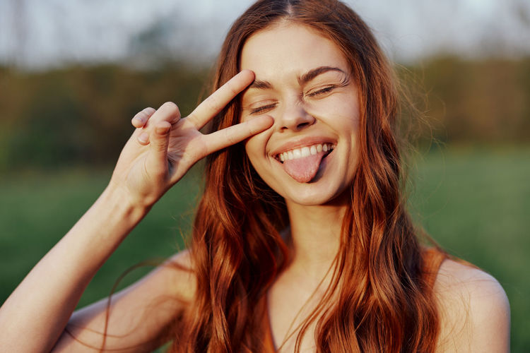 Woman sticking out tongue showing peace sign