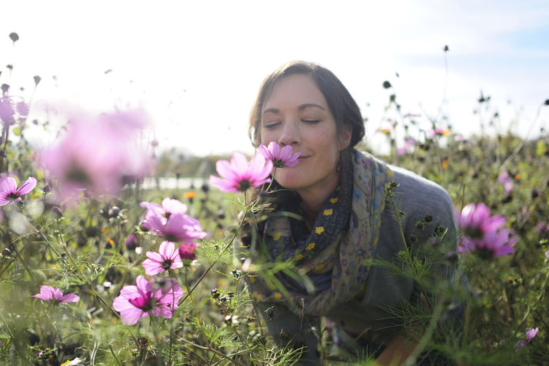 young woman blowing flowers on field