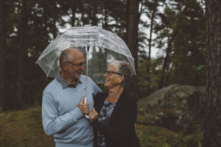 Elderly couple under an umbrella in the woods