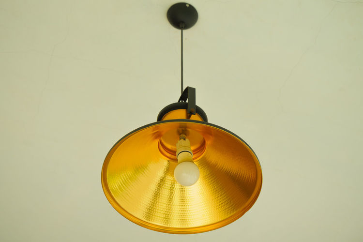 Low angle view of pendant light hanging against wall