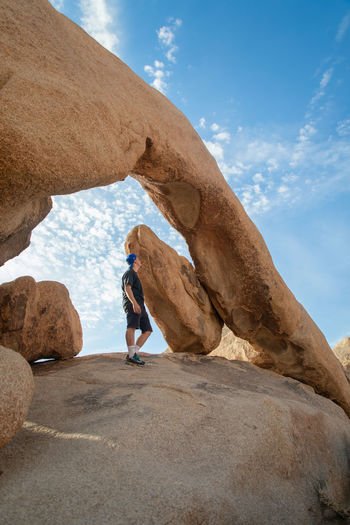 Low angle view of woman walking on rock formation against sky