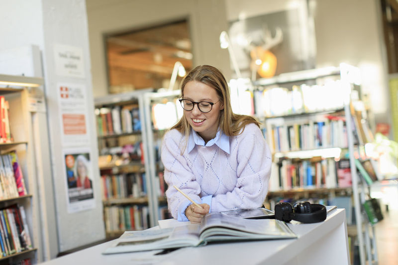 Portrait of young woman working in library