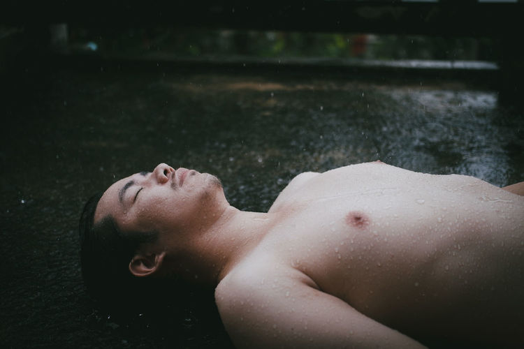 Side view of shirtless man lying in water