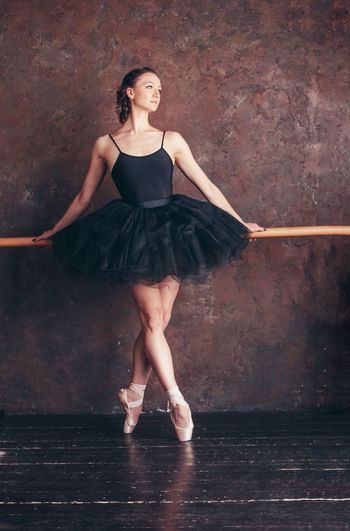 Full length of young woman dancing against wall in dance studio