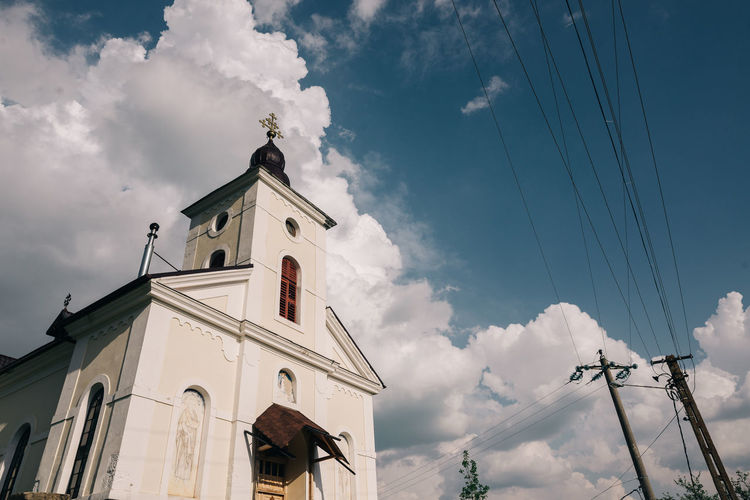 Low angle view of church against cloudy sky during sunny day