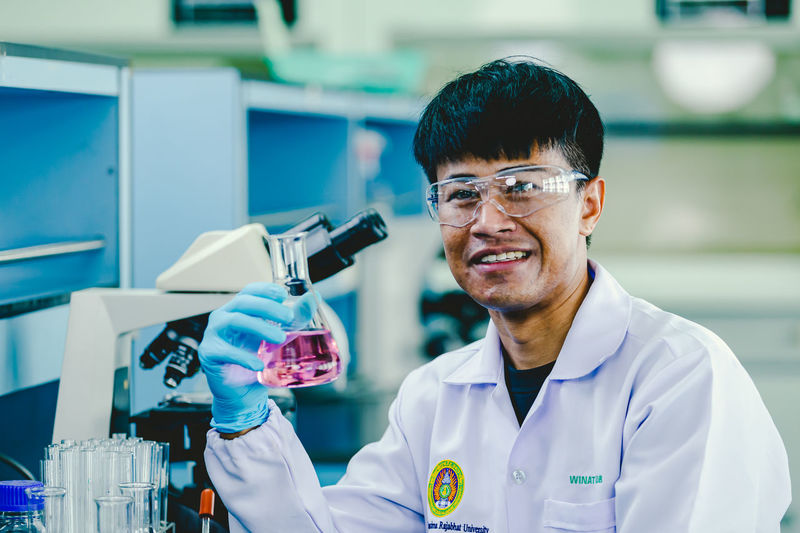 Cautious professional chemistry laboratory worker having erlenmeyer glass jars,medium shot.
