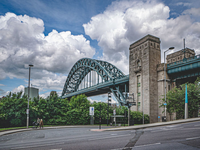 View of bridge and buildings against cloudy sky