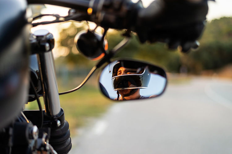 Man in the side view mirror of a motorbike