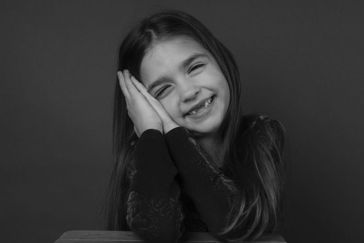 Portrait of smiling girl against black background