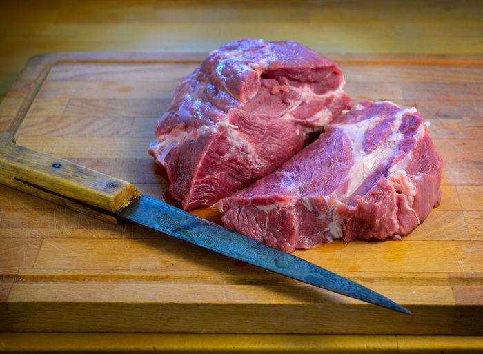 High angle view of meat on cutting board next to knife