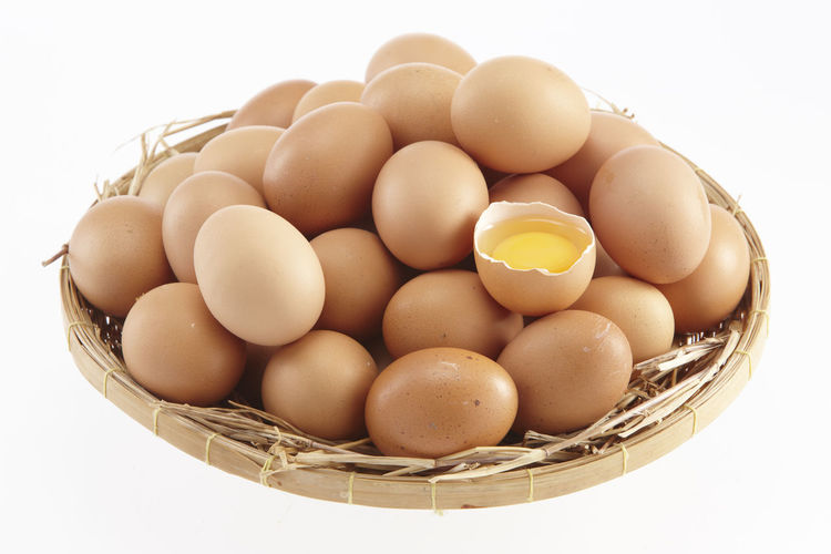 Close-up of eggs in basket against white background