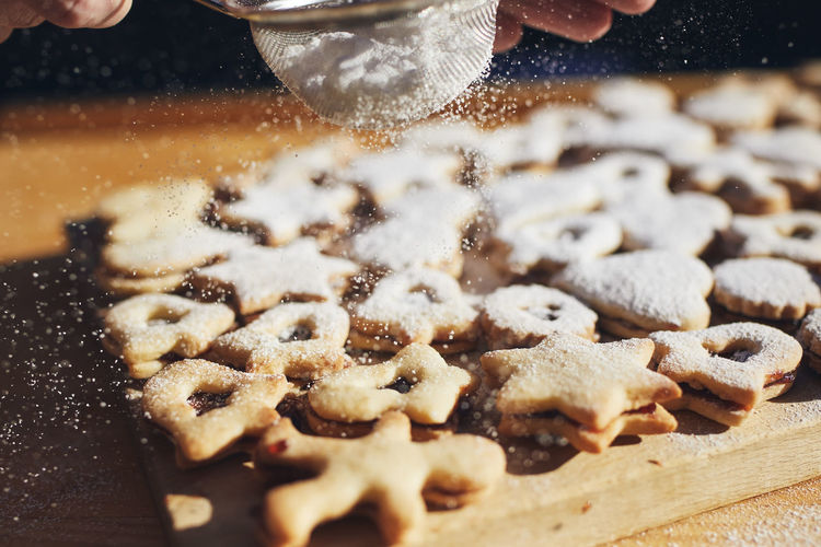Preparation of christmas sweets during advent. powdered sugar falling on linzer cookies.