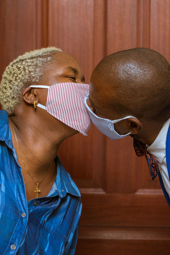 Portrait of a couple kissing wearing a face mask 