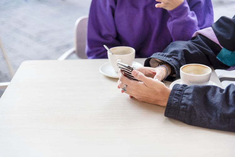 Midsection of woman using mobile phone on table