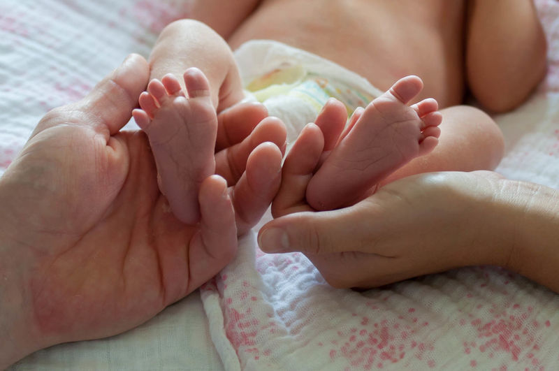 Cropped hands of parents holding baby feet
