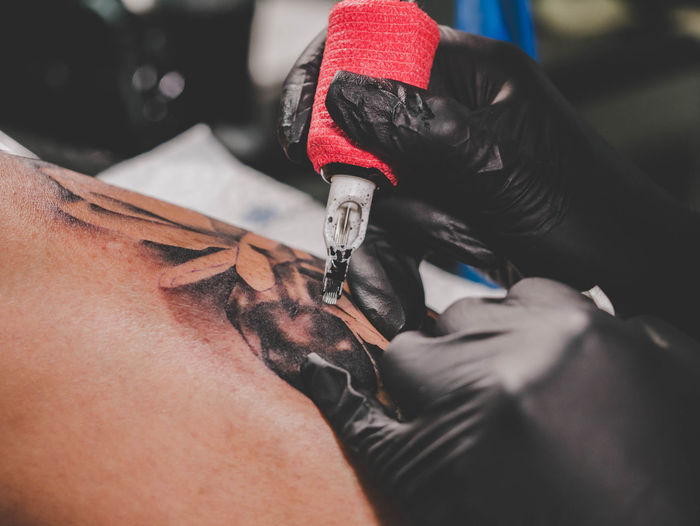 Cropped image of tattooist making tattoo on customer