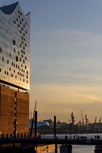 Buildings by river against sky during sunset