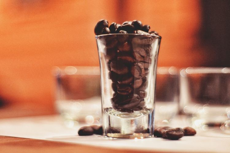 Close-up of roasted coffee beans in glass on table