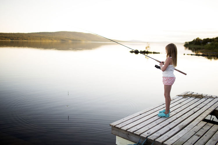 Full length of woman fishing in lake against sky