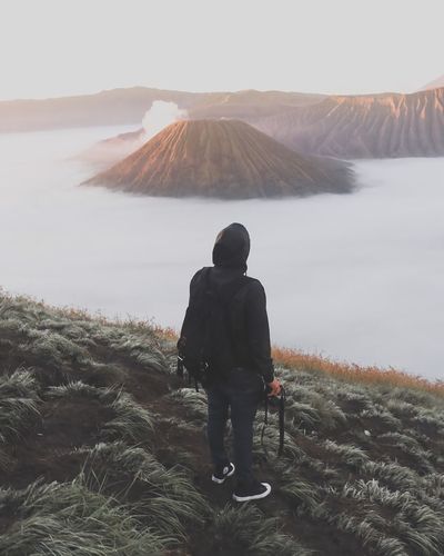 Rear view of male hiker standing on field at bromo-tengger-semeru national park