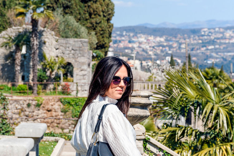 Portrait of beautiful  woman in mediterranean gardens. american gardens park in opatija, croatia.