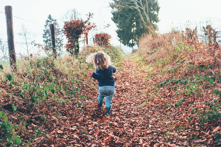 Rear view of girl running on field during autumn