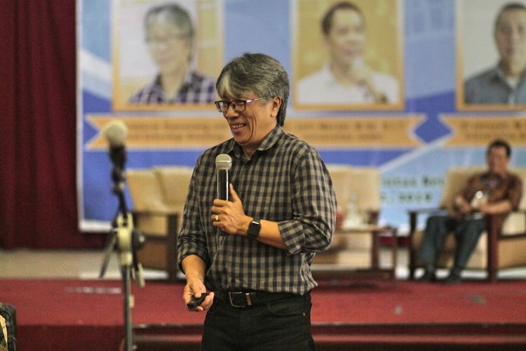 Smiling man giving speech while standing on stage