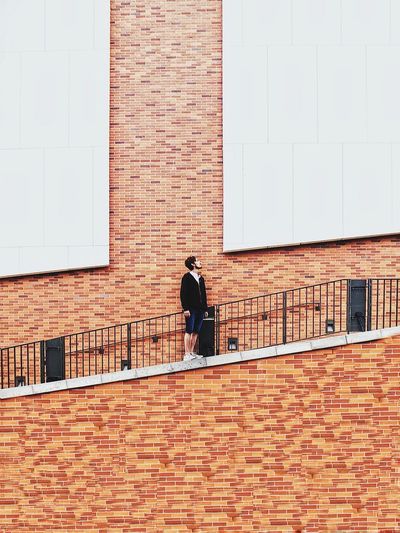 Low angle view of man standing on steps against brick wall