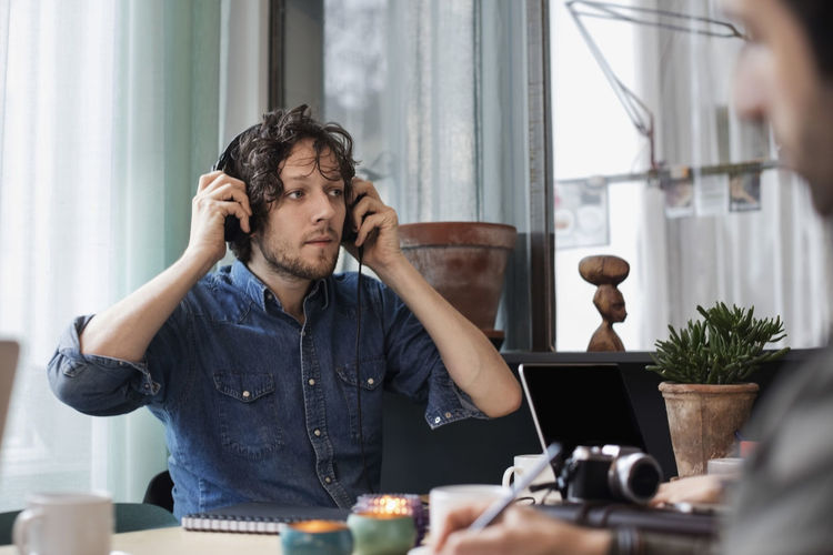 Creative man wearing headphones while sitting at table in office