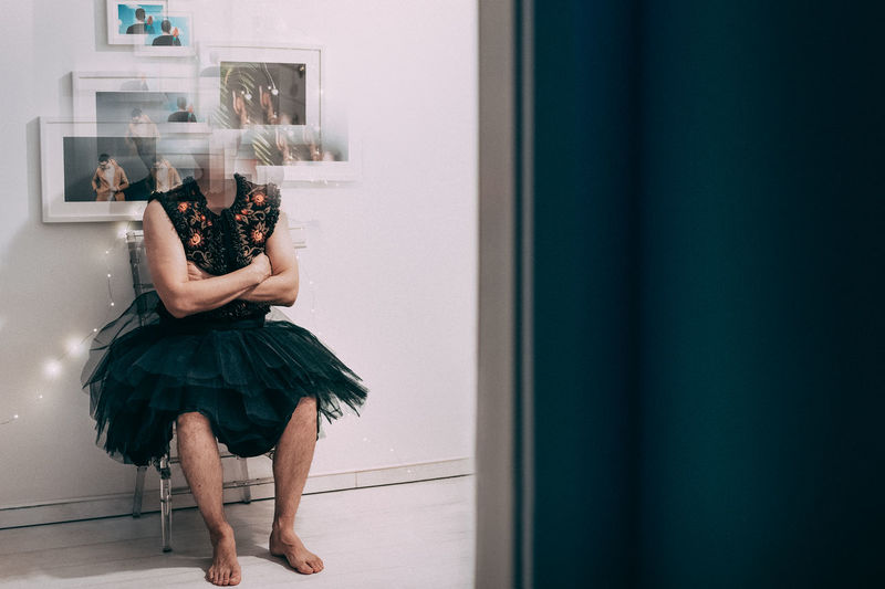Digital composite image of man wearing dress with frames by wall