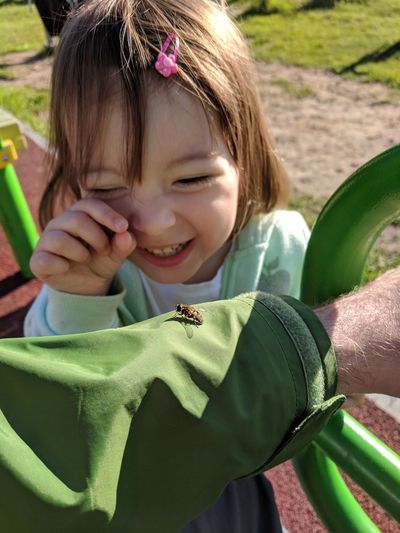 Happy girl catching insect on man hand