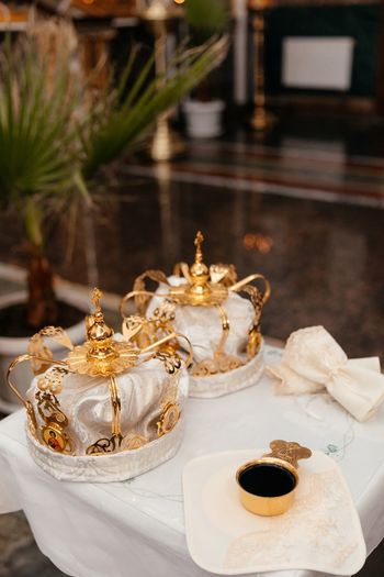 Golden crown of white fabric with a pattern lie on a table next to a golden cup