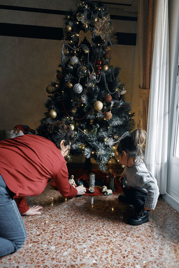 Grandparents decorate the christmas tree with their little granddaughter