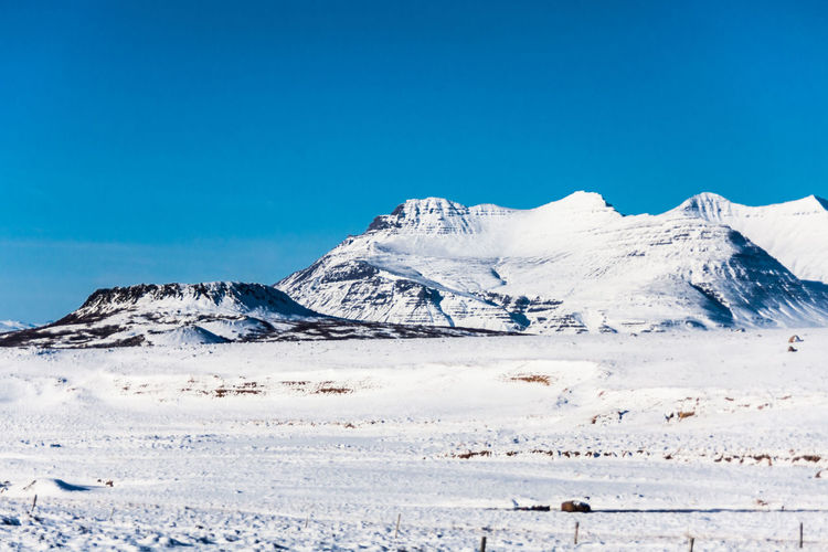 Scenic view of snowcapped mountains against clear blue sky