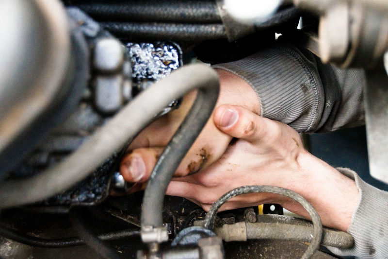 Cropped hand of mechanic repairing motor vehicle at auto repair shop