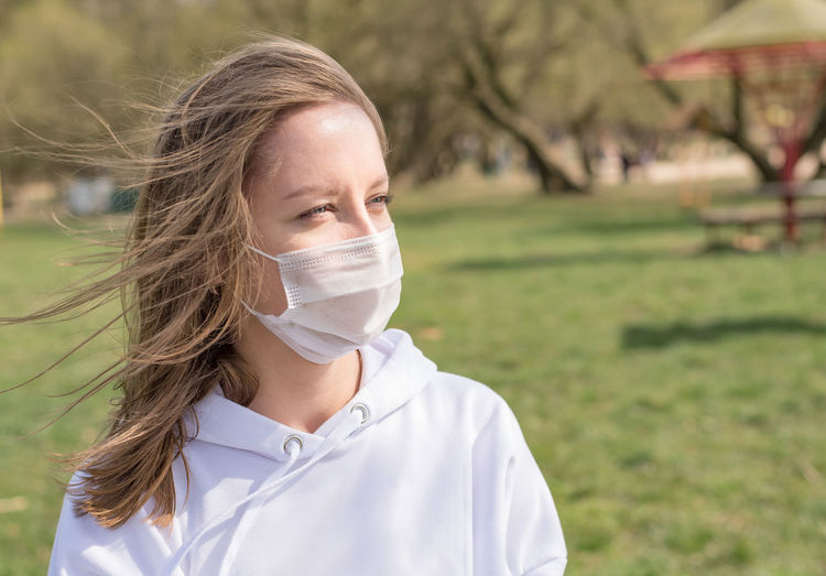 Girl, young woman in protective medical mask on her face in summer park.
