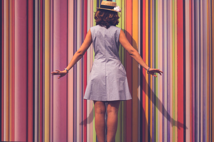 Rear view of a woman with multi colored curtain