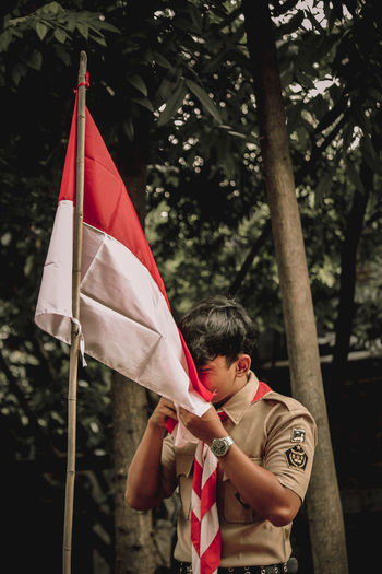 Soldier holding flag against tree