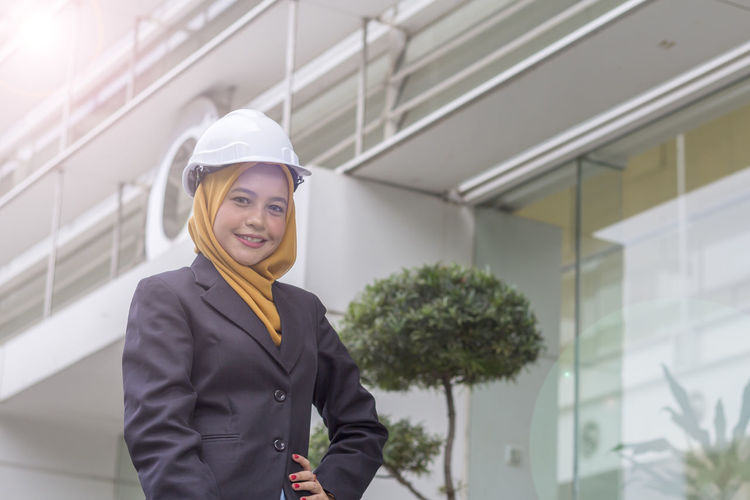 Low angle portrait of female architect standing against office building