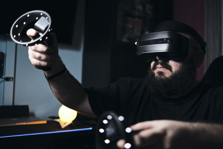 Man using vr glasses in a dark room at home.