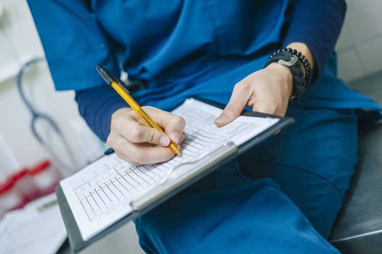 Female nurse writing medical report while sitting in hospital