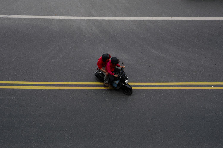 Low section of man riding push scooter on road