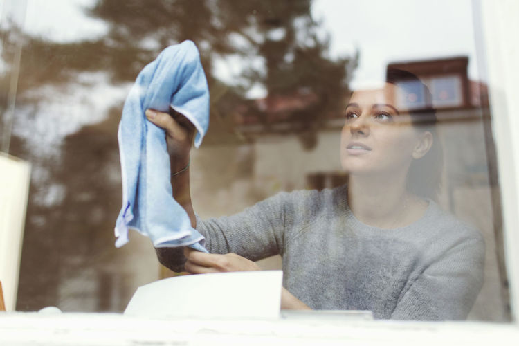 Woman cleaning glass of house window
